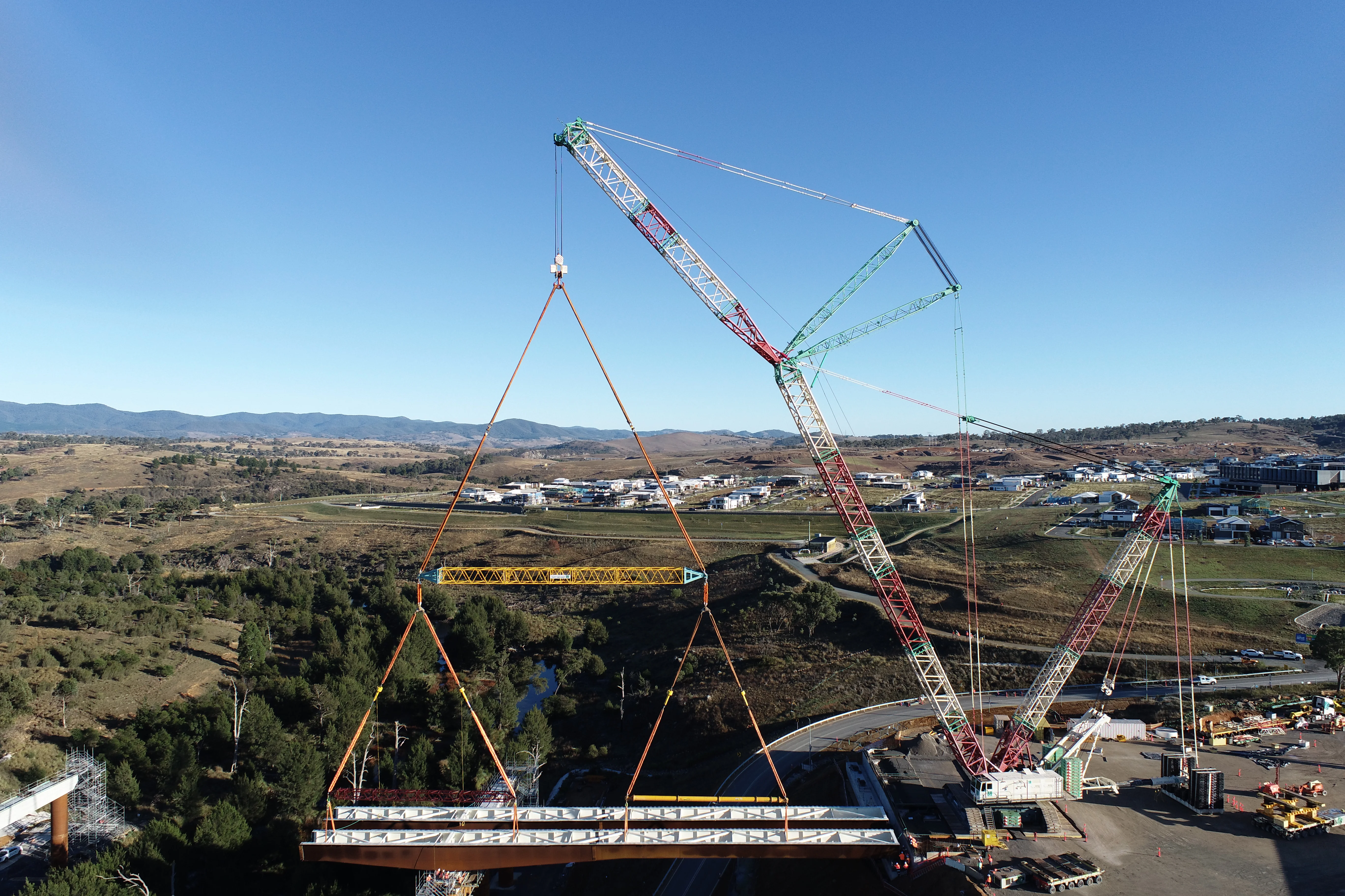 Aerial view of a crane lifting a girder span during Molonglo River Bridge construction